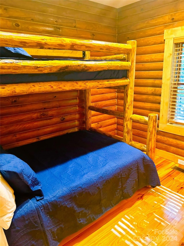 bedroom with hardwood / wood-style flooring and rustic walls