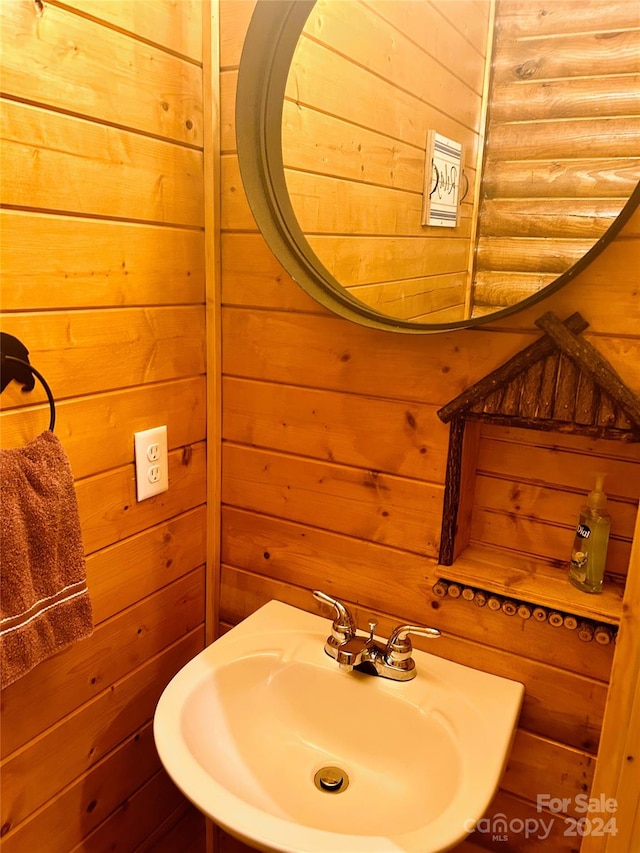 bathroom featuring sink and wooden walls