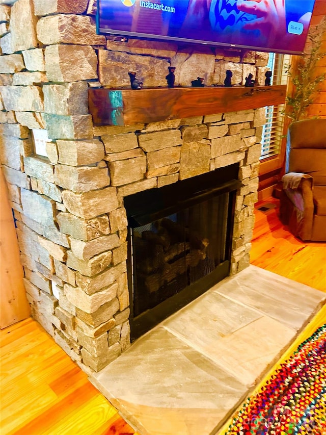 interior details featuring an outdoor stone fireplace and wood-type flooring