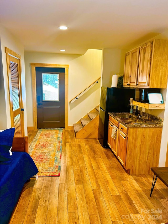 kitchen with light hardwood / wood-style floors, fridge, and dark stone counters