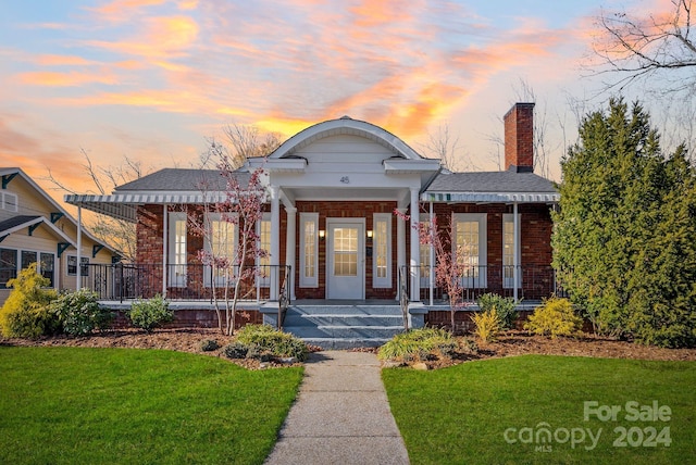 view of front of home with a porch and a lawn