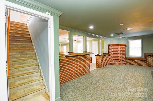 interior space featuring carpet floors, brick wall, and ornamental molding