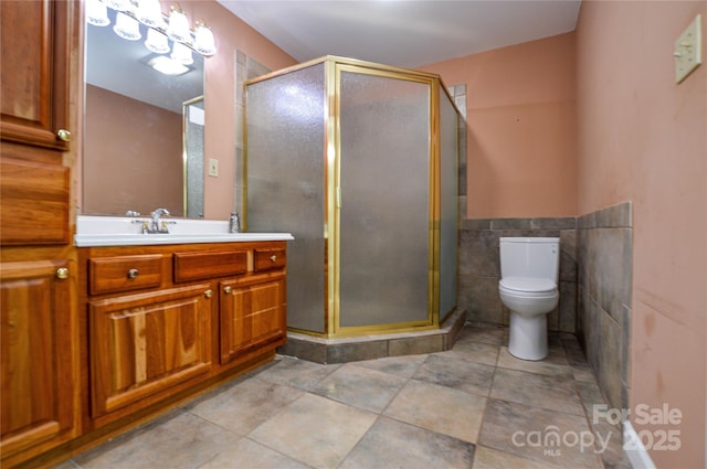 bathroom with a shower with shower door, toilet, and vanity