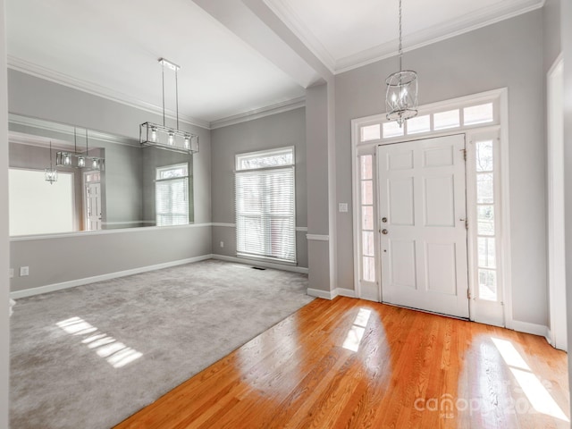 foyer entrance with crown molding, light colored carpet, and a notable chandelier