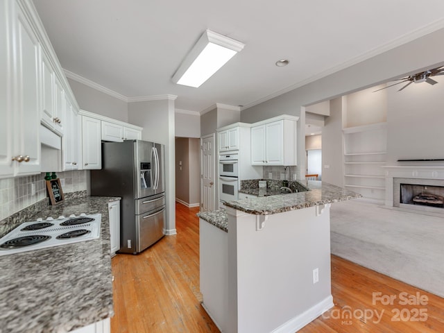 kitchen with white appliances, white cabinets, dark stone counters, decorative backsplash, and a kitchen breakfast bar