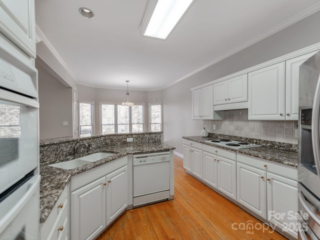 kitchen featuring decorative light fixtures, sink, white appliances, and white cabinets