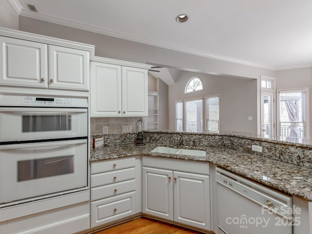 kitchen featuring white cabinets, white appliances, light stone countertops, and sink