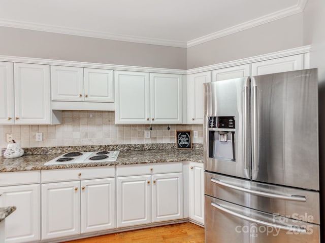 kitchen with white cabinets, stainless steel fridge, white electric cooktop, and tasteful backsplash