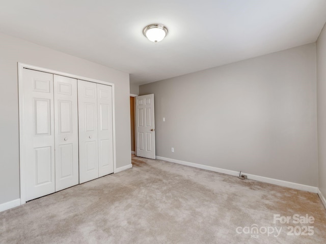 unfurnished bedroom with light carpet and a closet