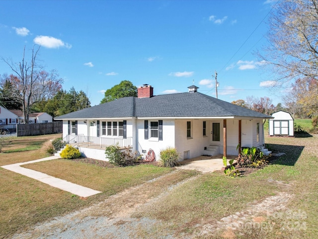 single story home featuring a front lawn, covered porch, and a shed