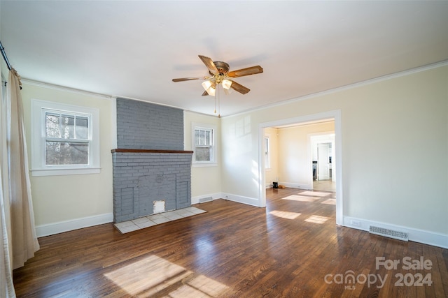 unfurnished living room featuring plenty of natural light, dark wood-type flooring, and a brick fireplace