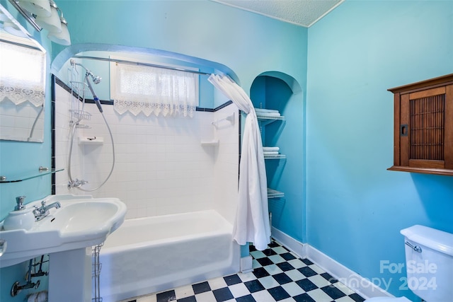 bathroom with shower / tub combo, a textured ceiling, and toilet