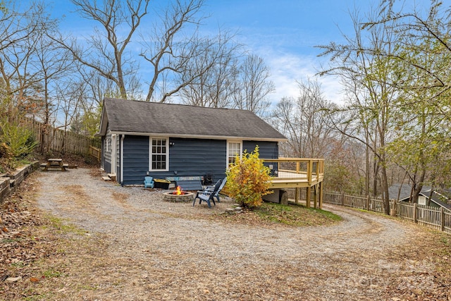 view of side of home featuring a wooden deck, an outdoor structure, and a fire pit