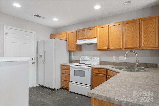 kitchen with a textured ceiling, white appliances, and sink