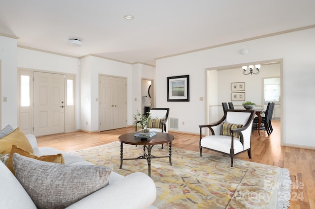 living room with light hardwood / wood-style floors, crown molding, and a notable chandelier