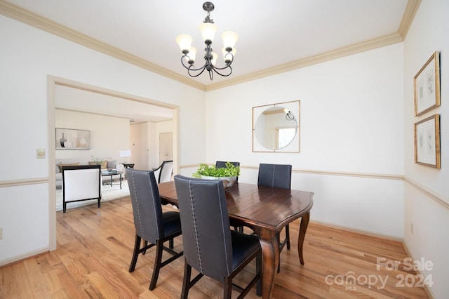 dining room with ornamental molding, light wood-type flooring, and an inviting chandelier