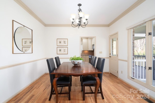 dining space featuring crown molding, a chandelier, and light wood-type flooring