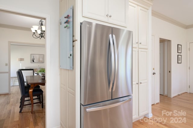 kitchen with a chandelier, ornamental molding, stainless steel refrigerator, and light hardwood / wood-style flooring