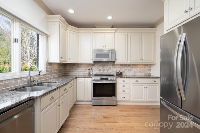 kitchen featuring sink, decorative backsplash, light wood-type flooring, appliances with stainless steel finishes, and stone countertops