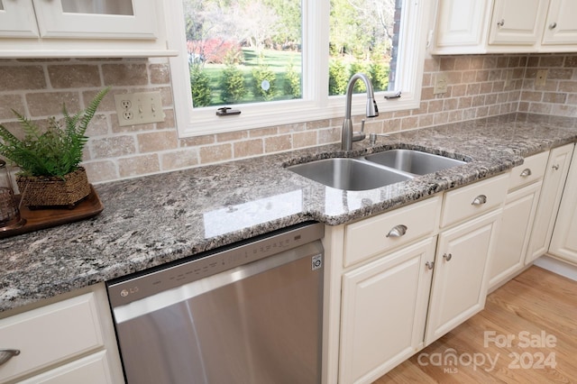 kitchen featuring sink, stainless steel dishwasher, light stone countertops, light wood-type flooring, and white cabinetry