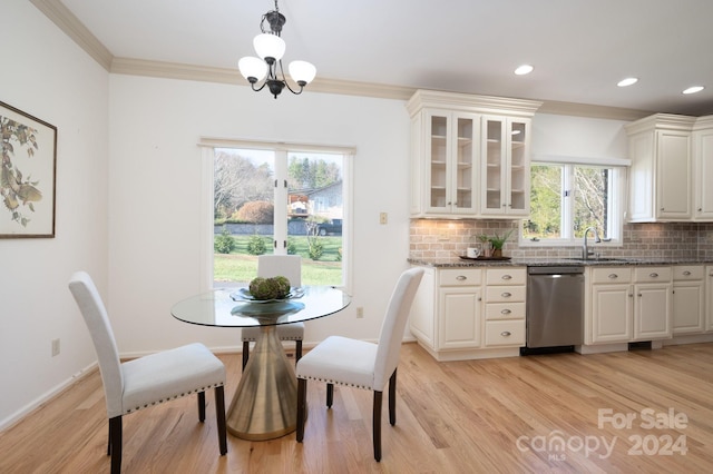 dining area with crown molding, light hardwood / wood-style flooring, an inviting chandelier, and sink