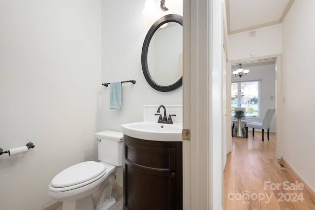 bathroom with hardwood / wood-style floors, vanity, toilet, and a chandelier