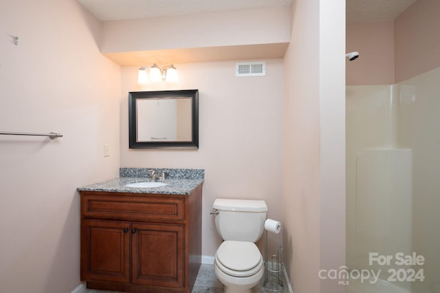 bathroom featuring vanity, toilet, and a textured ceiling