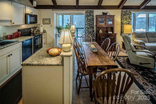 300 Glenwood Ln Unit K-38, Sugar Mountain, NC 28604 - kitchen with black appliances, open floor plan, beam ceiling, light stone countertops, and a kitchen island