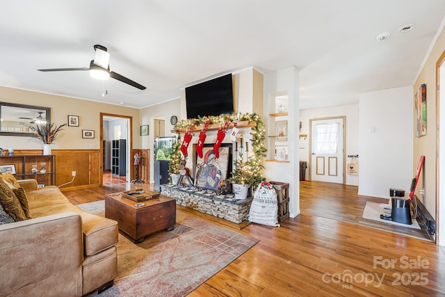 living room with hardwood / wood-style floors, ceiling fan, and wood walls