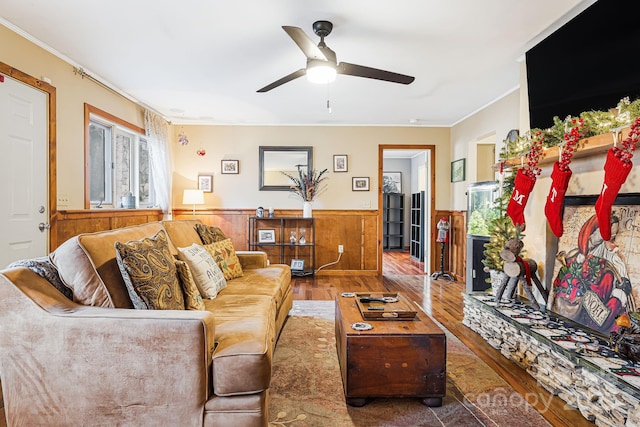 living room with wood-type flooring, wooden walls, ceiling fan, and crown molding