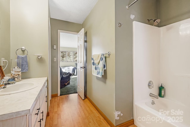 bathroom featuring a textured ceiling, vanity, hardwood / wood-style flooring, and  shower combination