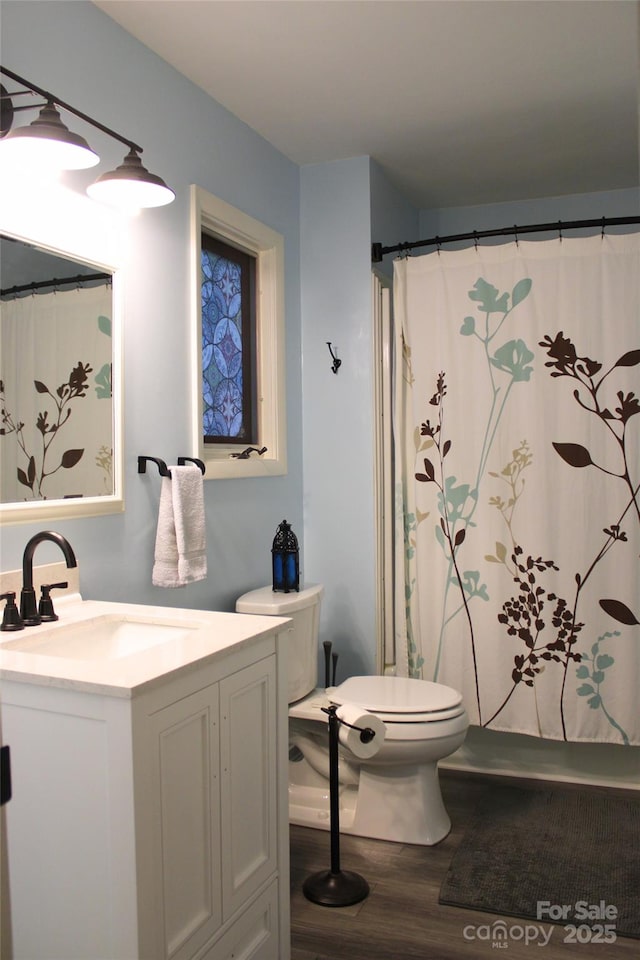 full bath featuring toilet, vanity, a shower with shower curtain, and wood finished floors