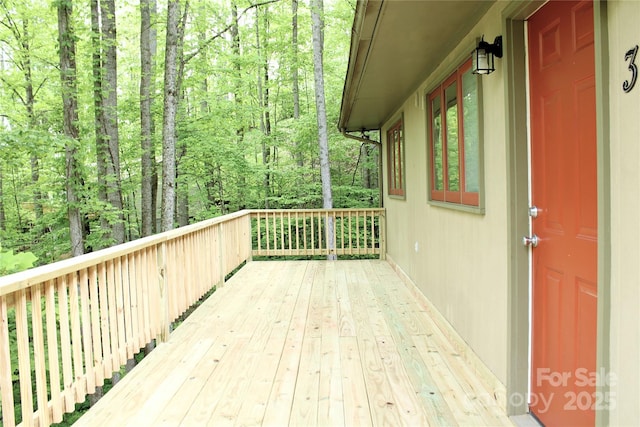 wooden terrace featuring a wooded view