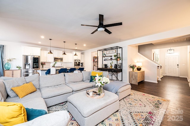 living area featuring ceiling fan, recessed lighting, dark wood-style flooring, baseboards, and stairs