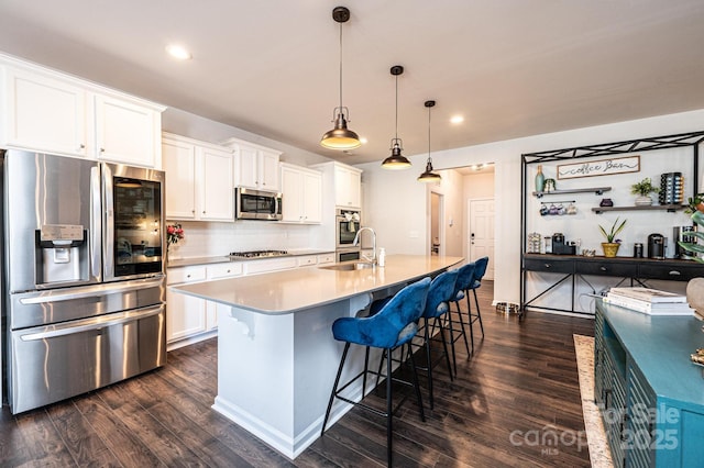 kitchen with stainless steel appliances, dark wood-type flooring, a sink, and white cabinetry