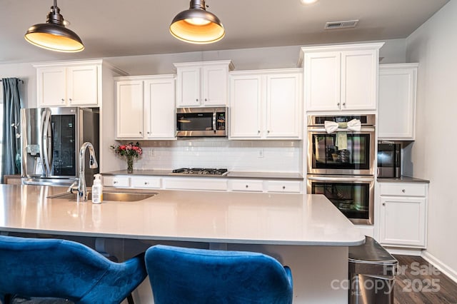 kitchen with stainless steel appliances, white cabinets, a sink, and decorative backsplash