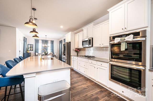 kitchen featuring a breakfast bar, dark wood finished floors, stainless steel appliances, backsplash, and a sink