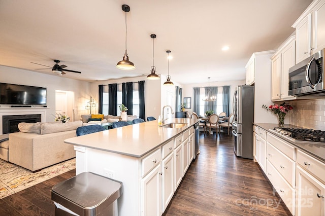 kitchen with dark wood-style floors, decorative backsplash, stainless steel appliances, and a sink