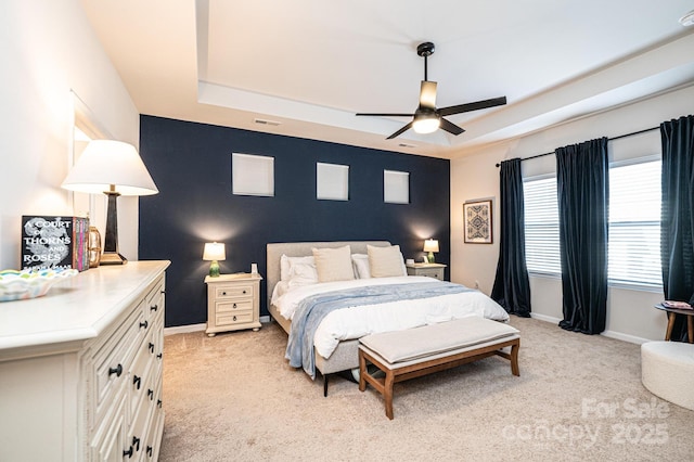 bedroom with light carpet, baseboards, and a tray ceiling