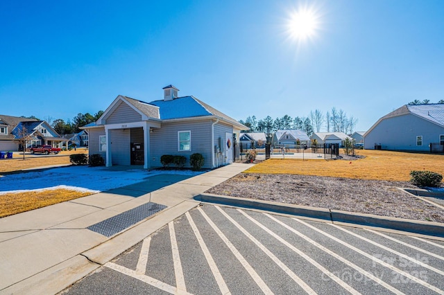 view of front of house featuring a residential view, fence, and a front lawn