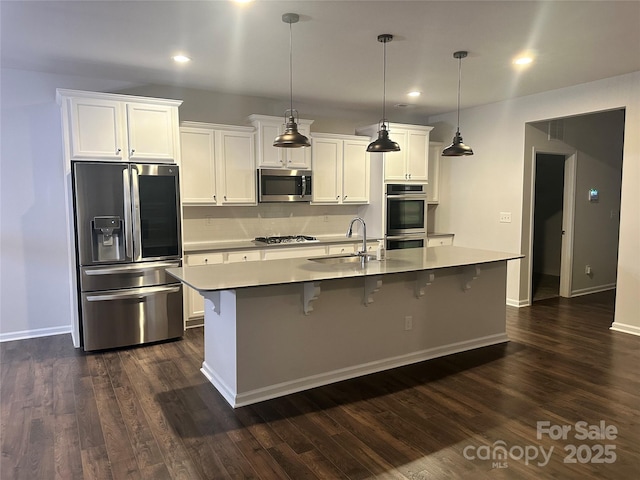 kitchen with stainless steel appliances, dark wood-style flooring, a sink, and white cabinets