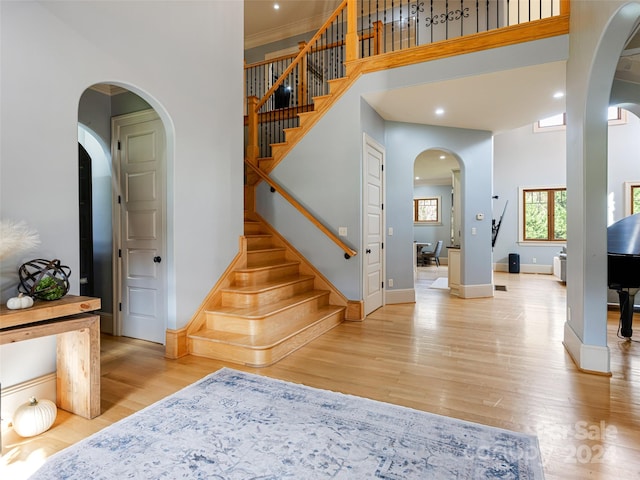 foyer with a towering ceiling, light hardwood / wood-style floors, and ornamental molding