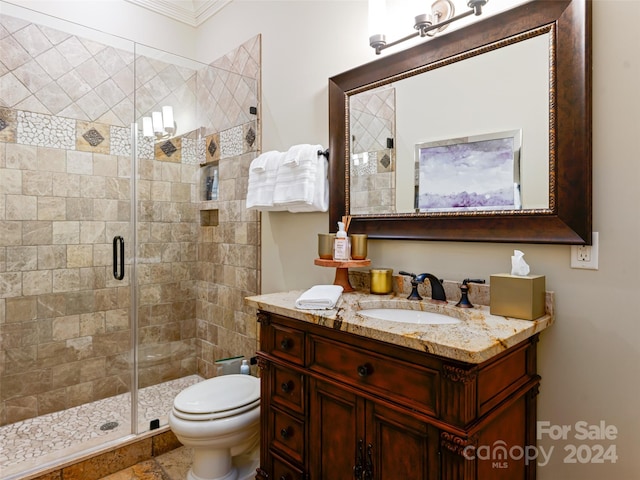 bathroom with ornamental molding, vanity, toilet, and a shower with shower door