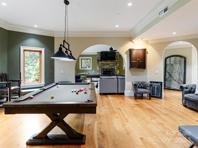 game room with light hardwood / wood-style floors, a stone fireplace, crown molding, and pool table