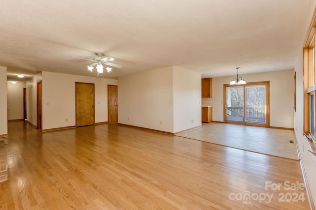 unfurnished living room featuring a textured ceiling, light hardwood / wood-style flooring, and ceiling fan with notable chandelier