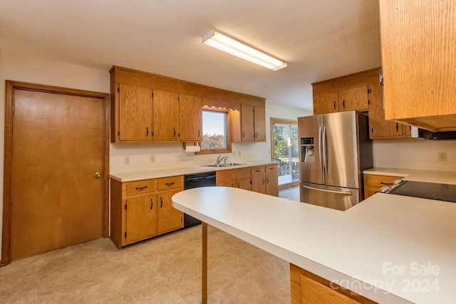 kitchen featuring a textured ceiling, stainless steel fridge, sink, and black dishwasher