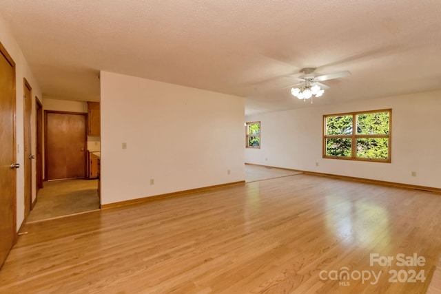 unfurnished room with ceiling fan, light hardwood / wood-style floors, and a textured ceiling