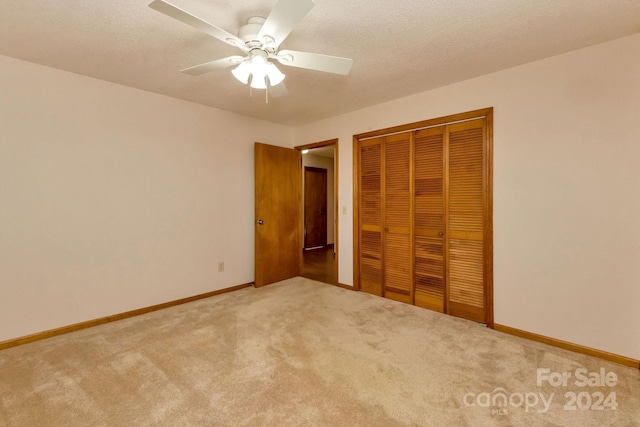 unfurnished bedroom featuring ceiling fan, carpet floors, a textured ceiling, and a closet