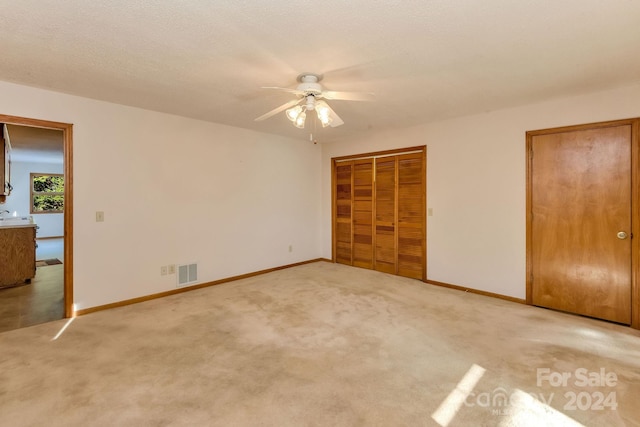 unfurnished bedroom featuring a textured ceiling, carpet floors, and ceiling fan