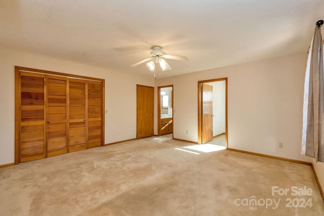 unfurnished bedroom featuring connected bathroom, ceiling fan, and light carpet